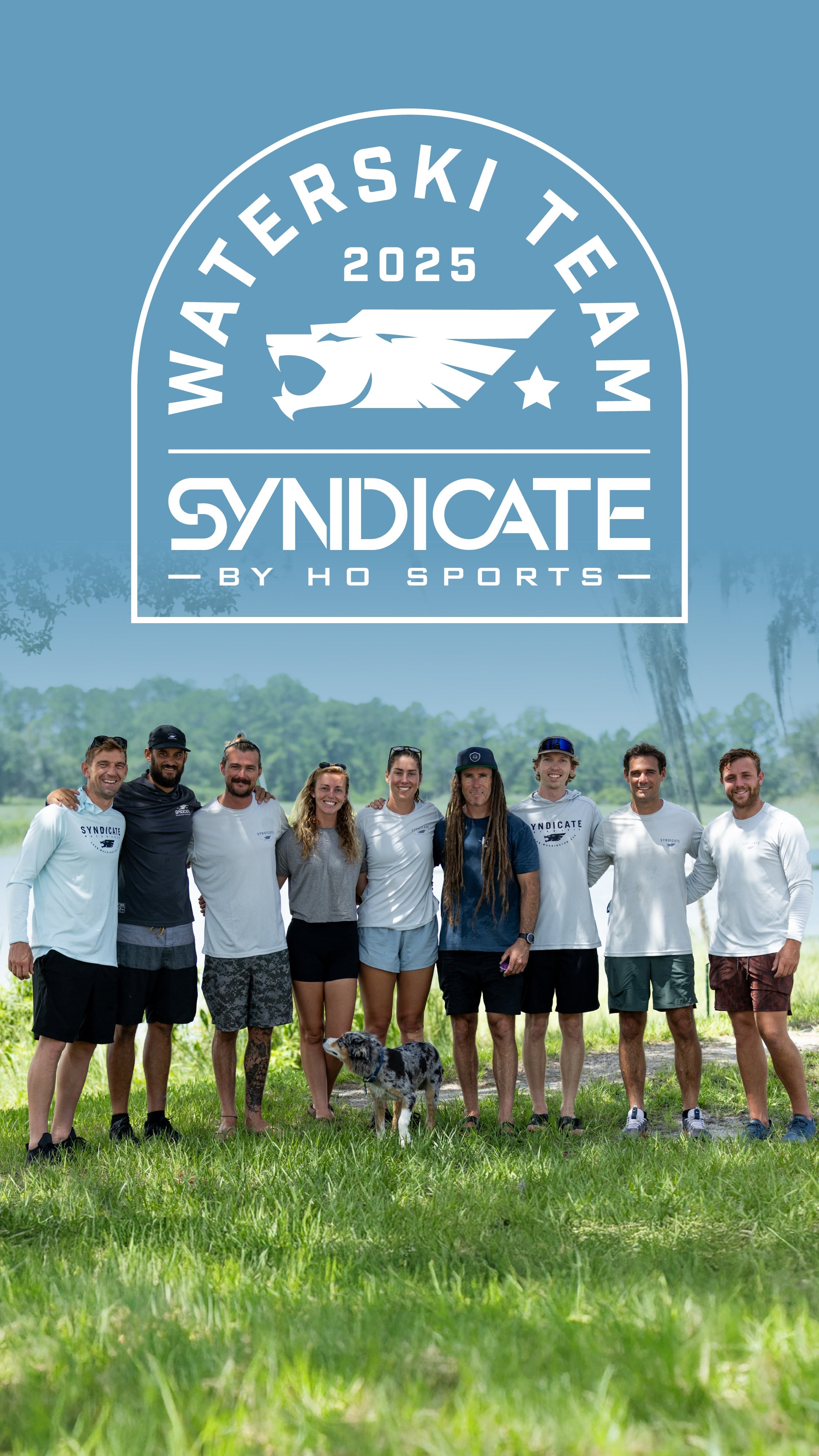 Nine athletes in Syndicate apparel stand on grass with a dog. The team logo is above them on a blue background.